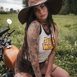Woman with tattoos sitting on a motorcycle in a field wearing clothing designed by Soul Sister since 1969