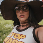 Person wearing a 'Top Wars' tank top and large hat in a field. Designed by Soul Sister since 1969