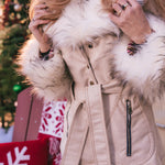 Person wearing a beige Penny lane vintage 70s inspired coat with white fur trim in a festive setting.