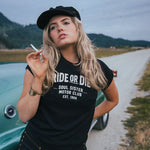 Woman wearing a 'Ride or Die' t-shirt on a road with mountains in the background Ride or Die Motor Club wearing soul sister since 1969