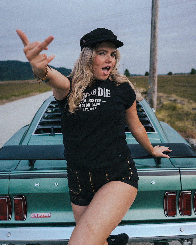 Woman posing in front of a vintage car on a road trip