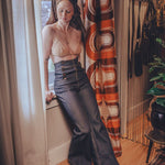 Woman in a room with a patterned curtain and wooden floor.