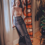 Woman in a room with a patterned curtain and wooden floor.