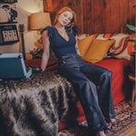 Woman sitting on a couch in a cozy living room with a laptop.