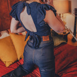 Person wearing a blue denim outfit with a visible brand logo, standing on a red couch.