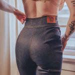 Person wearing a brown textured top and dark jeans with a visible brand logo.