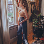 Woman standing by a window in a cozy room with decor elements.