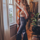 Woman in a stylish outfit standing by a window in a room with decorative elements.