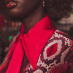 Close-up of a person wearing a patterned garment with a bright red bow tie.