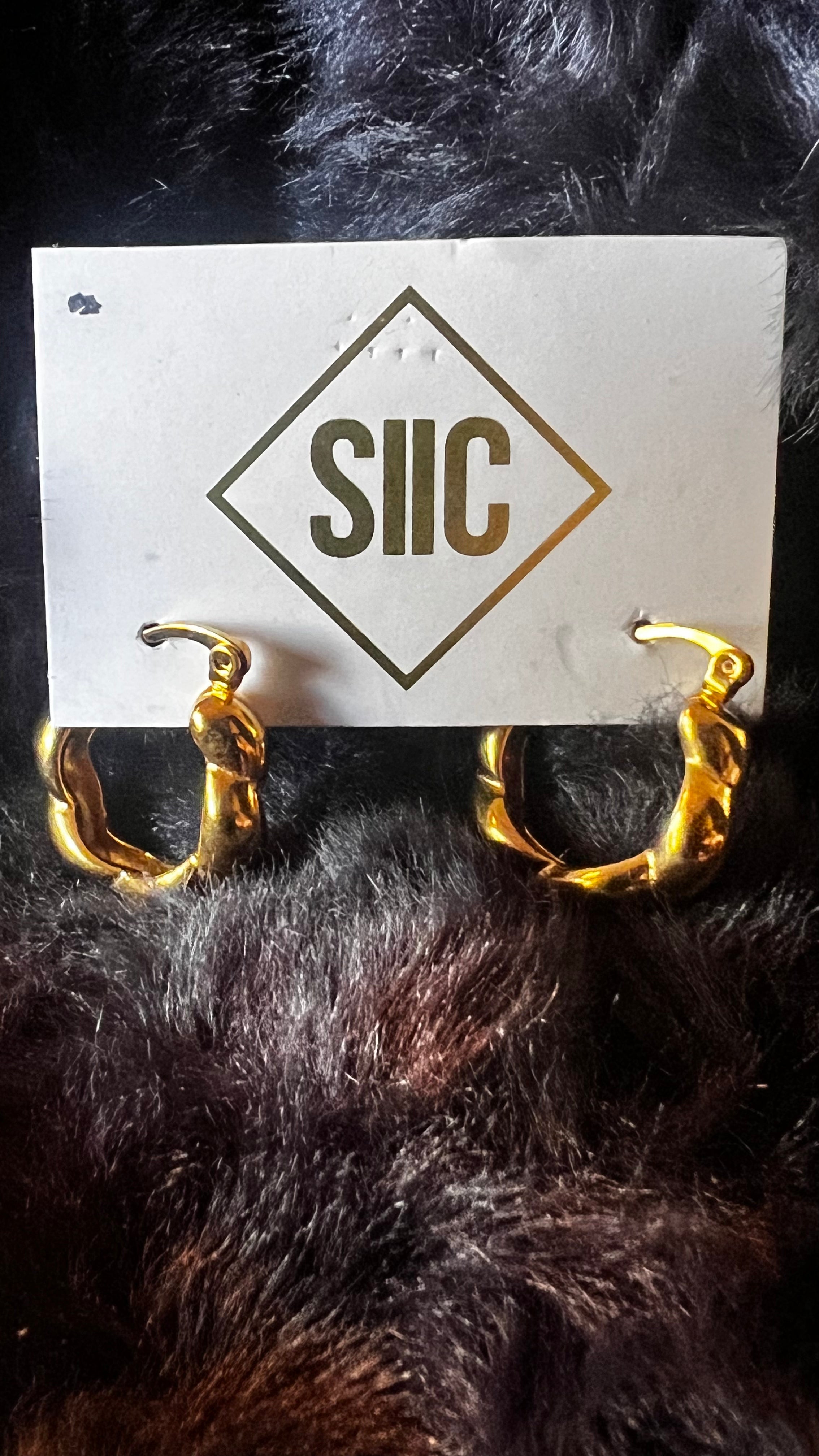 Gold hoop earrings on a card with 'SIIC' branding against a dark background