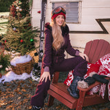 Woman in ski gear sitting on a red chair in front of a trailer with 'JOY' decoration and Christmas tree.