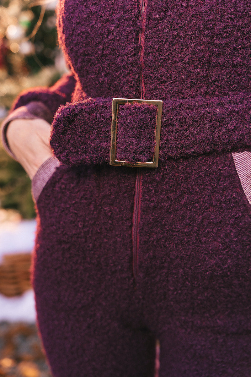 Close-up of a person wearing a purple coat with a gold buckle, blurred background