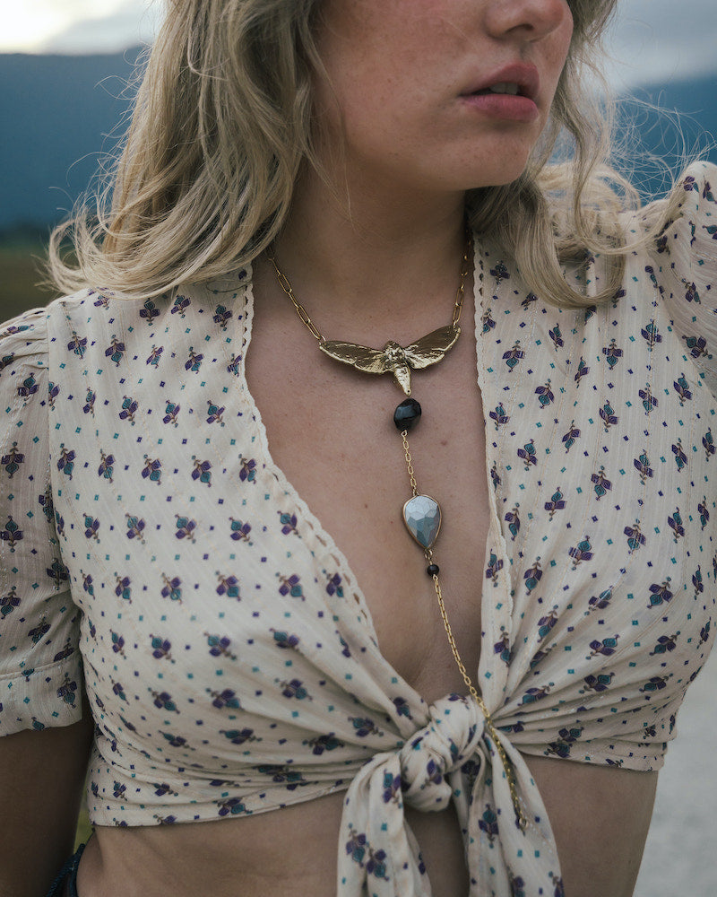 Woman wearing a floral blouse and a necklace with a butterfly pendant wearing Soul Sister since 1969.