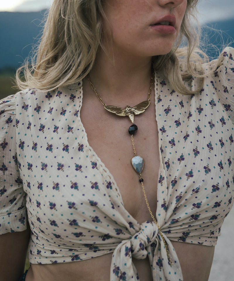 Woman wearing a floral blouse and a necklace with a butterfly pendant wearing Soul Sister since 1969.