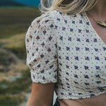 Person wearing a floral blouse with a blurred natural background wearing Soul Sister since 1969.