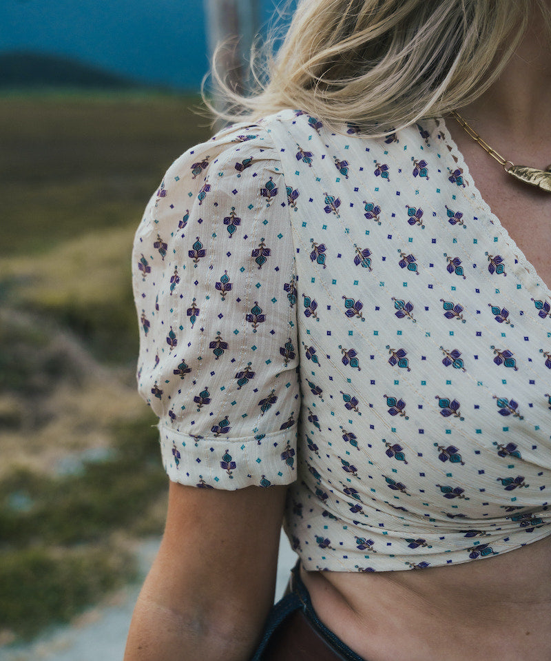 Person wearing a floral blouse with a blurred natural background wearing Soul Sister since 1969.
