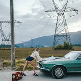 Person leaning against a vintage car with power lines and mountains in the background wearing soul sister since 1969