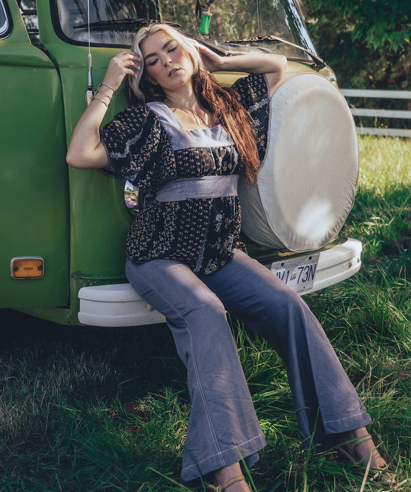 Girl sits at the front of a 1970s VW Van wearing 70s fashion jeans and blouse
