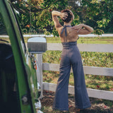 A person posing by a fence wearing high waisted bell bottoms and a sleeveless top.