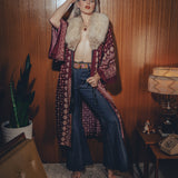 Bellbottom jeans are worn by a model in a retro styled 1970s living room

