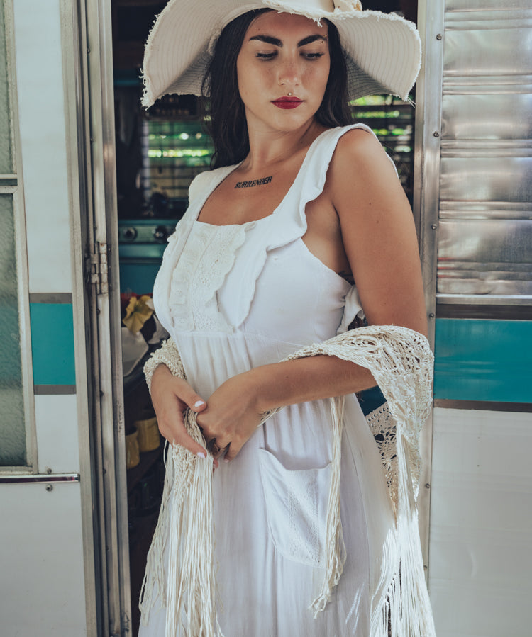 Soul Sister since 1969 long white dress on beautiful woman with a fringe shawl and retro floppy hat standing in a vintage trailer
