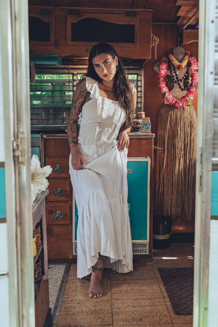 Soul Sister since 1969 long white dress on beautiful woman with a fringe shawl and retro floppy hat standing in a vintage trailer