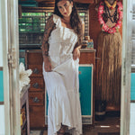 Soul Sister since 1969 long white dress on beautiful woman with a fringe shawl and retro floppy hat standing in a vintage trailer