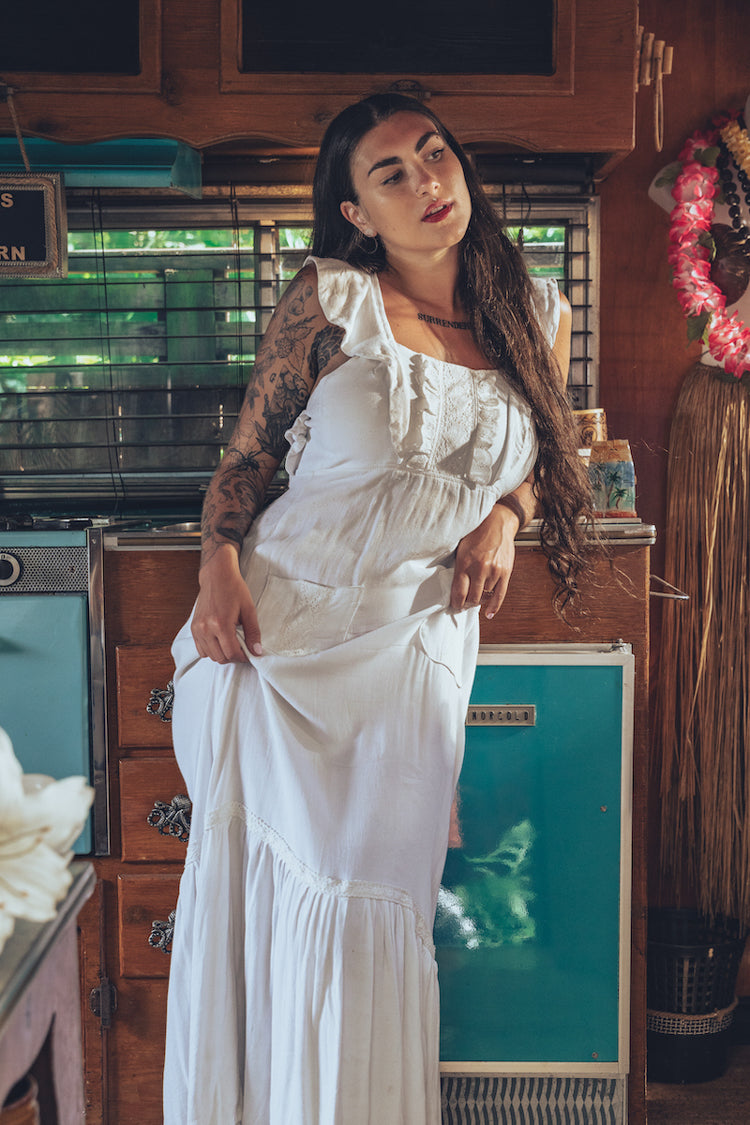 Soul Sister since 1969 long white dress on beautiful woman with a fringe shawl and retro floppy hat standing in a vintage trailer