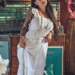 Soul Sister since 1969 long white dress on beautiful woman with a fringe shawl and retro floppy hat standing in a vintage trailer