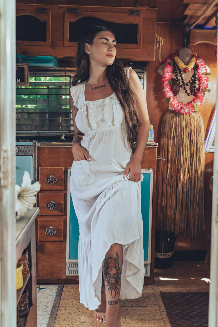 Soul Sister since 1969 long white dress on beautiful woman with a fringe shawl and retro floppy hat standing in a vintage trailer