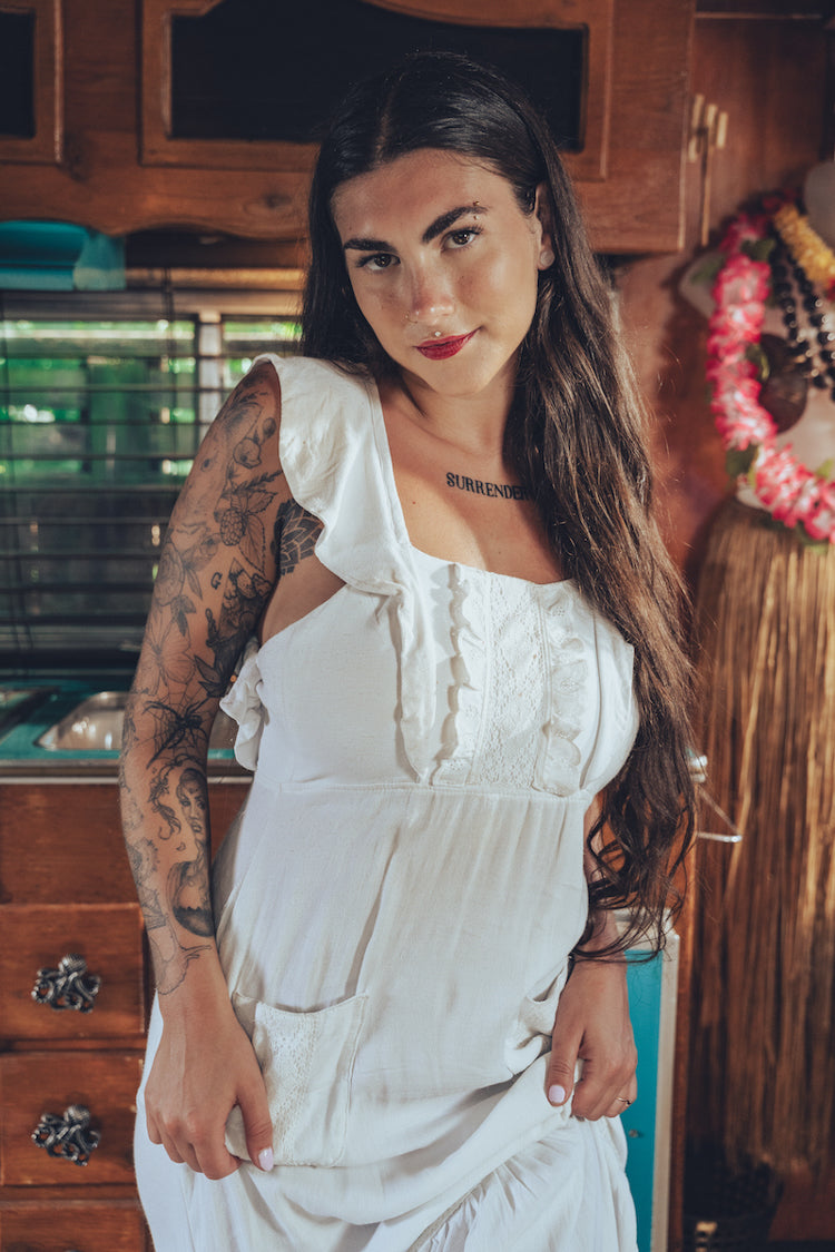 Soul Sister since 1969 long white dress on beautiful woman with a fringe shawl and retro floppy hat standing in a vintage trailer