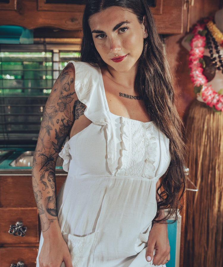Soul Sister since 1969 long white dress on beautiful woman with a fringe shawl and retro floppy hat standing in a vintage trailer