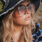 Woman wearing a black witch hat and sunglasses with a blurred natural background wearing Soul Sister since 1969.