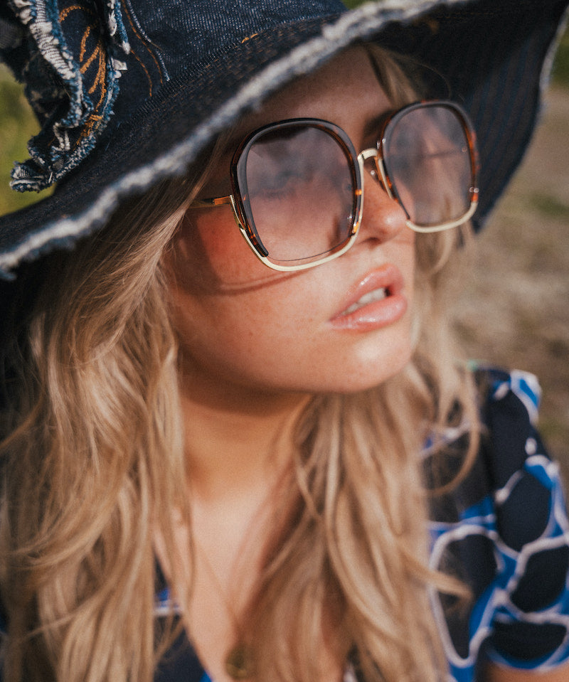 Woman wearing a black witch hat and sunglasses with a blurred natural background wearing Soul Sister since 1969.
