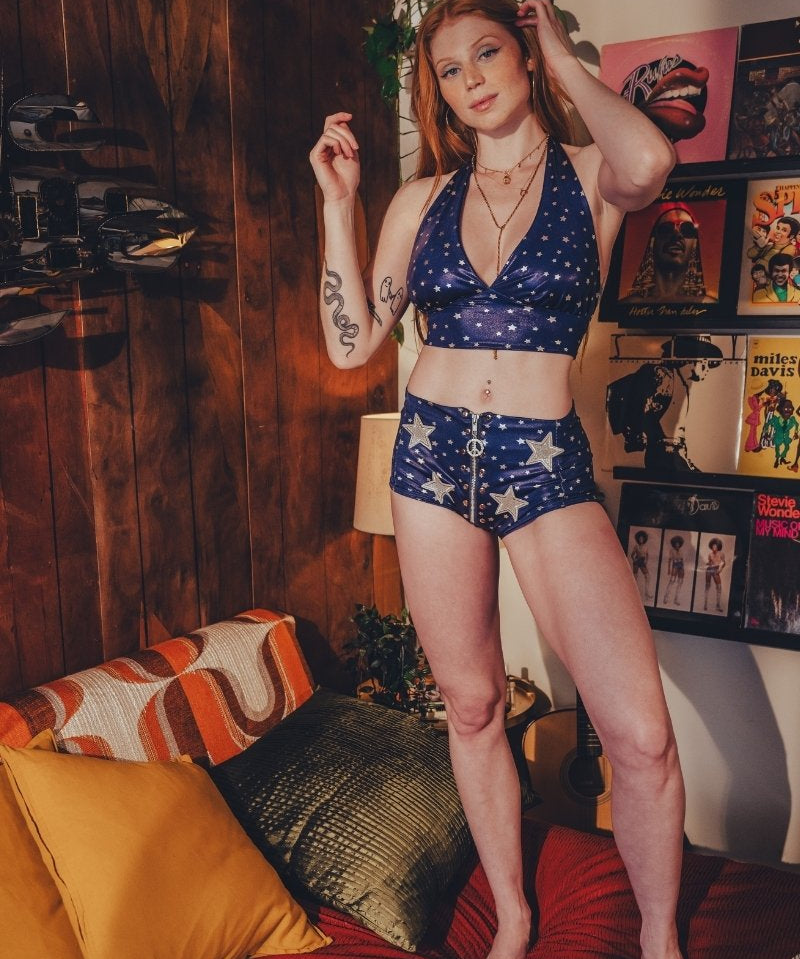 Woman in a blue and white star-patterned outfit standing in a room with a couch and decorative items.