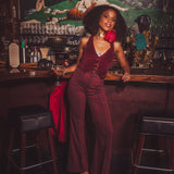 Woman in a burgundy outfit standing behind a bar with a vintage decor.