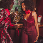 Two women in festive attire standing in a bar setting with drinks.