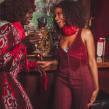 Two women in festive attire standing in a bar setting with drinks.