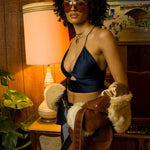 Beautiful woman in a retro 1970s living room wearing sunglasses and groovy jeans and halter top