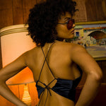 Beautiful woman in a 1970s retro living room wearing funky bellbottoms and a backless halter top