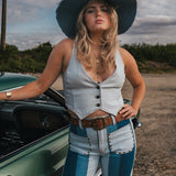 Woman in a white top and blue jeans standing next to a green car on a dirt road wearing Soul Sister since 1969..