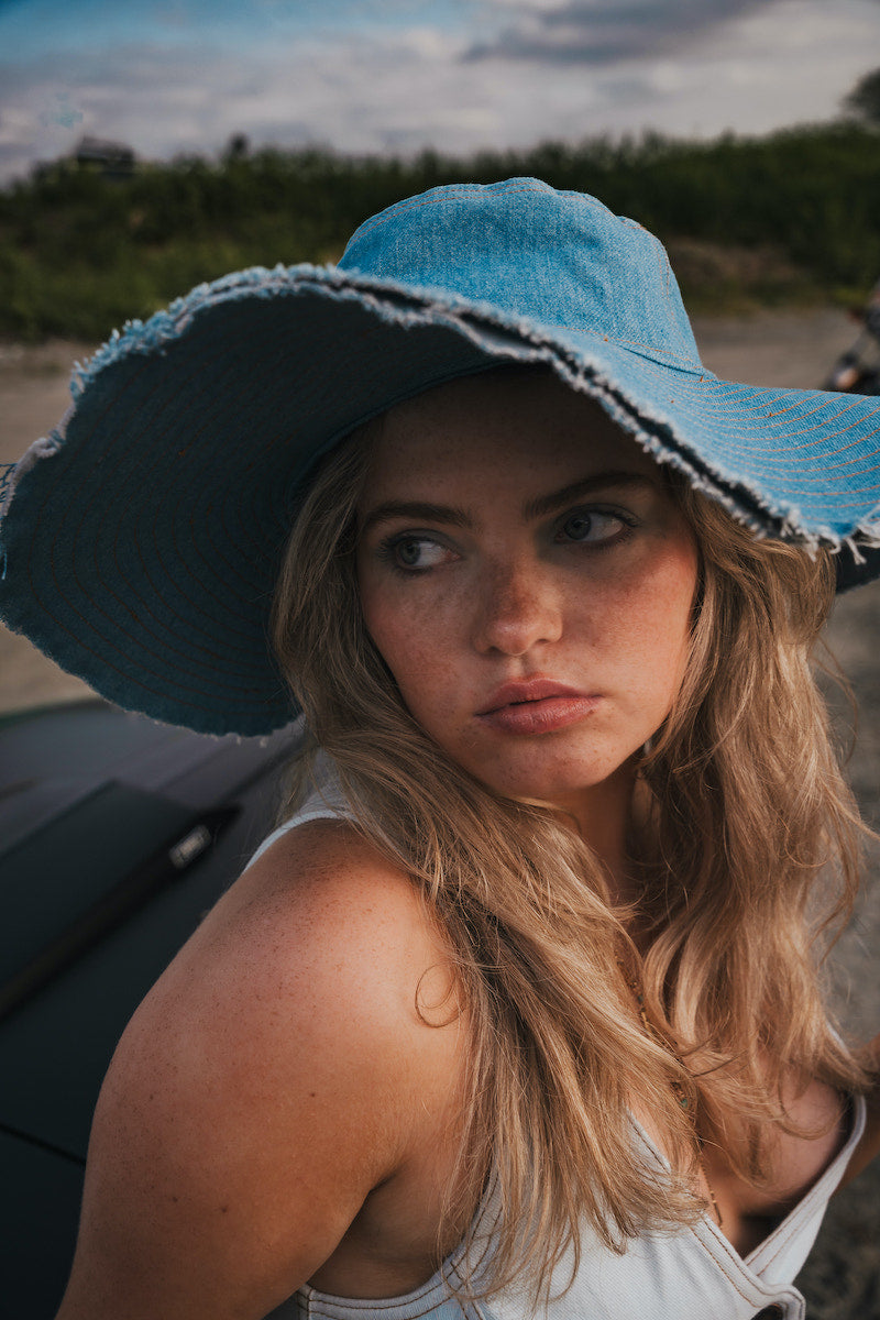 Woman wearing a blue sun hat with a blurred background wearing Soul Sister since 1969