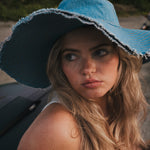 Woman wearing a blue sun hat with a blurred background wearing Soul Sister since 1969