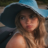 Woman wearing a blue sun hat with a blurred background wearing Soul Sister since 1969