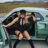 Woman in a stylish outfit sitting in an open car door with a scenic background wearing Soul Sister since 1969