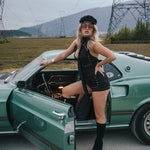 Woman in a black outfit standing next to a green car with power lines and mountains in the background wearing Soul Sister since 1969