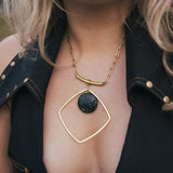 Gold necklace with a black pendant worn by a person