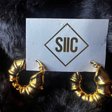 Gold hoop earrings on a card with 'SIIC' logo against a black fur background