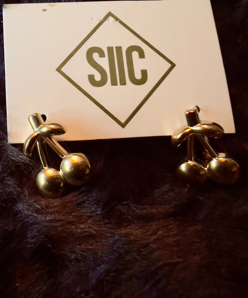Gold earrings on a card with 'SIIC' logo on a dark fur background