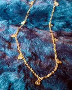 Gold necklace with small beads on a blue fur background